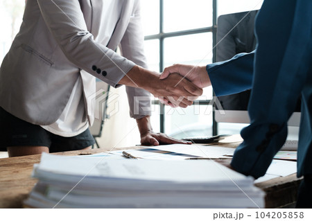 Handshake as successful negotiation ending, close-up. Unknown business people shaking hands after contract signing in modern office Handshake as successful negotiation ending, close-up. Unknown business people shaking hands after contract signing in modern office 104205858