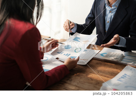 Team of two asian male and female business people working together discussing new financial graph data on office table with laptop and digital tablet. 104205863