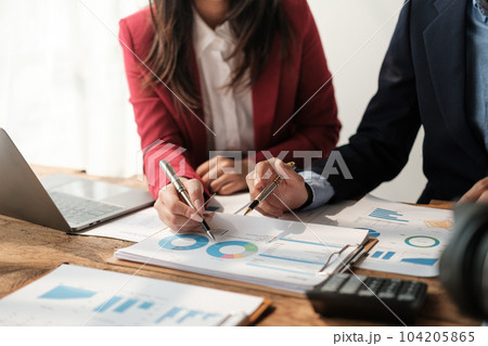 Team of two asian male and female business people working together discussing new financial graph data on office table with laptop and digital tablet. 104205865