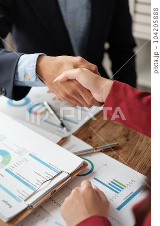 Handshake as successful negotiation ending, close-up. Unknown business people shaking hands after contract signing in modern office 104205888
