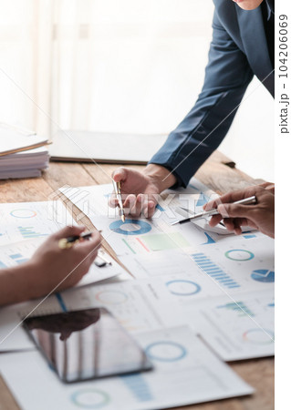 Close up group of business men and woman discussion and brainstorming, bookkeeping audit graph and chart documents at desk, teamwork concept. 104206069
