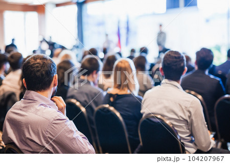 Speaker giving a talk in conference hall at business event. Rear view of unrecognizable people in audience at the conference hall. Business and entrepreneurship concept Speaker giving a talk in conference hall at business event. Rear view of unrecognizable people in audience at the conference hall. Business and entrepreneurship concept 104207967