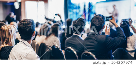 Speaker giving a talk in conference hall at business event. Rear view of unrecognizable people in audience at the conference hall. Business and entrepreneurship concept Speaker giving a talk in conference hall at business event. Rear view of unrecognizable people in audience at the conference hall. Business and entrepreneurship concept 104207974