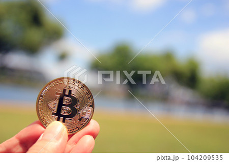 Bitcoin gold coin, Hand hold bitcoin in the park and natural background 104209535