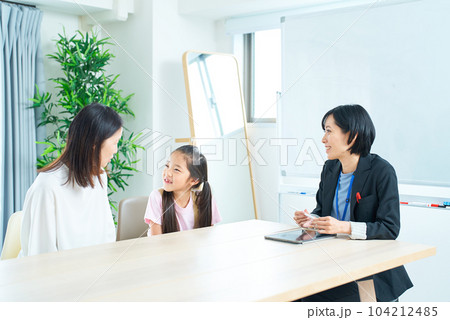 親子とスーツ姿の女性の会話シーン 104212485