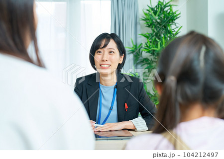 親子とスーツ姿の女性の会話シーン 104212497