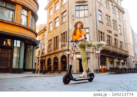 Woman on vacation having fun driving electric scooter through city. Ecological transport concept. Woman on vacation having fun driving electric scooter through city. Ecological transport concept. 104213774