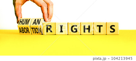 Abortion rights symbol. Concept words Abortion rights are human rights on wooden cubes. Businessman hand. Beautiful yellow table white background. Business medical abortion rights concept. Copy space. Abortion rights symbol. Concept words Abortion rights are human rights on wooden cubes. Businessman hand. Beautiful yellow table white background. Business medical abortion rights concept. Copy space. 104213945
