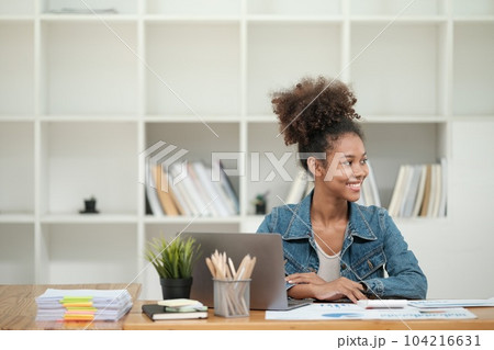 Smart African women working in beautiful office, working on Laptop, use the phone, talking on the cellphone.  104216631