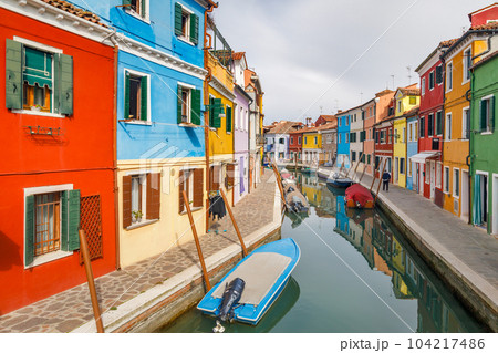 The Burano island near Venice, a canal with colorful houses. 104217486
