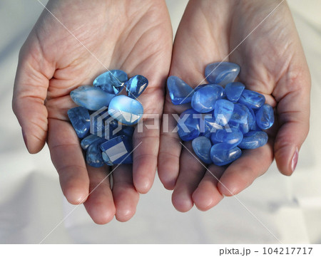 両手に乗せた青い天然石、パワーストーンを持っている様子 104217717