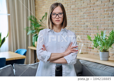 Portrait of young positive woman with arms crossed, in living room 104218885