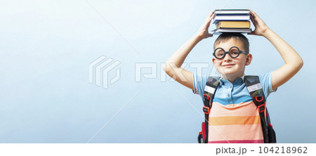 Funny school boy in glasses holding books on his head 104218962