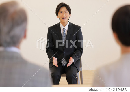 転職_面接で緊張しながら小さな身振りで話す30代のビジネスマン_1 104219488