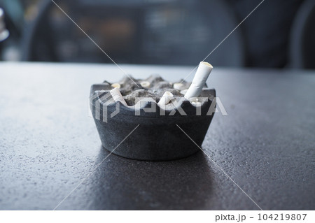 Close up burning cigarette in ashtray on table Close up burning cigarette in ashtray on table 104219807
