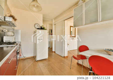 a kitchen with red chairs and a white refrigerator in the corner next to the counter top is a clock on the wall a kitchen with red chairs and a white refrigerator in the corner next to the counter top is a clock on the wall 104221128
