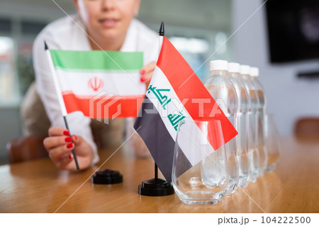 Unrecognizable girl sets midget flags of Iraq and Iran before international negotiations 104222500