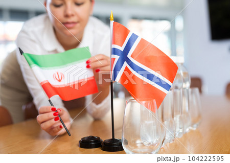 Little flag of Norway on table and flag of Iran put next to it by young woman 104222595