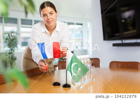 Positive young woman putting little flag of France on table next to the flag of Pakistan 104222879