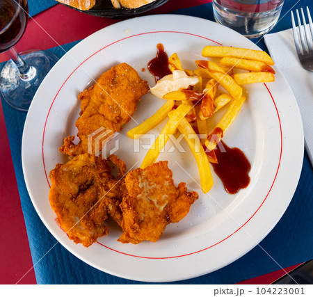 Breaded chicken breast with french fries closeup 104223001