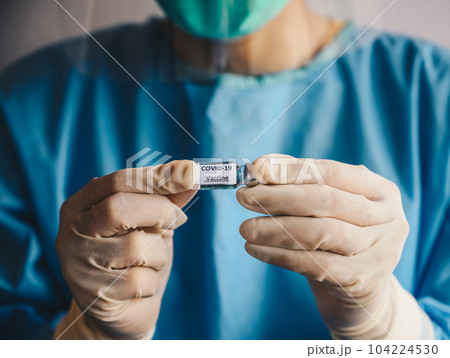 Close up of scientist doctor hand holding a sample test bottle of Covid-19 vaccine. Close up of scientist doctor hand holding a sample test bottle of Covid-19 vaccine. 104224530