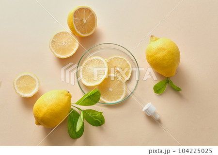 Promotional scene for cosmetics and skin care products with natural vitamin c - fresh lemon, lime slices and green leaves decoration on a beige background. 104225025