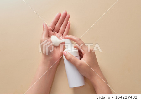 Female hand model take the white foam mousse from unbranded pump bottle in white color. Branding cleanser mockup over beige background Female hand model take the white foam mousse from unbranded pump bottle in white color. Branding cleanser mockup over beige background 104227482