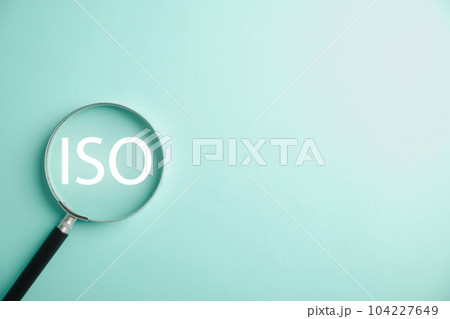 A magnifying glass is used to magnify the word ISO, highlighting its importance in standardization and security control. efforts of professionals in using technology and adhering to ISO 9001 standards 104227649