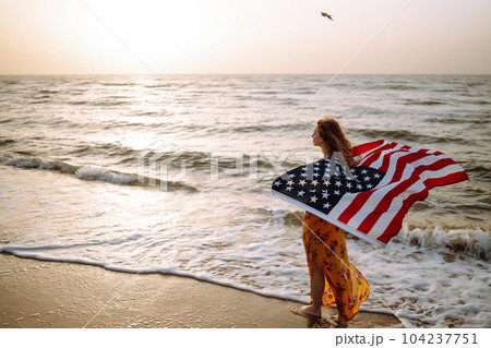 Young woman with american flag on the beach at sunset. 4th of July. Independence Day. Young woman with american flag on the beach at sunset. 4th of July. Independence Day. 104237751