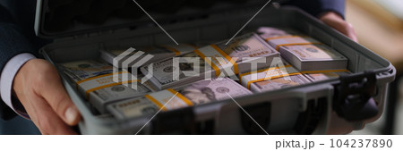 Banker holding suitcase with many dollar bills closeup Banker holding suitcase with many dollar bills closeup 104237890