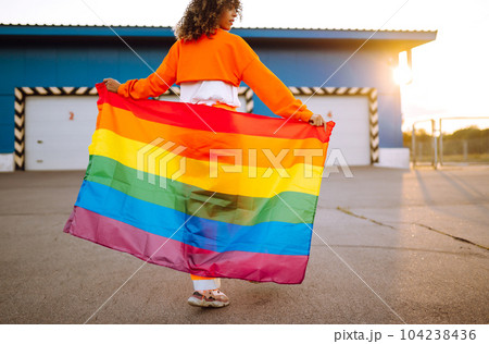 African American lesbian woman holding LGBT rainbow flag. The concept of happiness, freedom and love for same-sex couples. 104238436