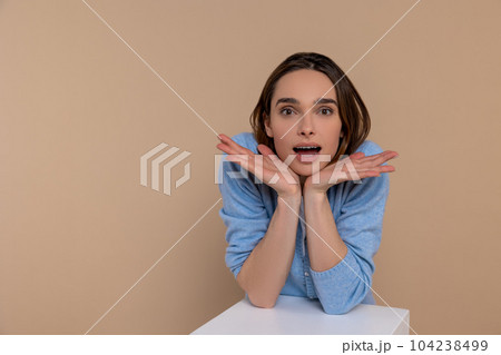 Surprised woman in casual clothing with hands under chin saying wow being astonished Surprised woman in casual clothing with hands under chin saying wow being astonished 104238499