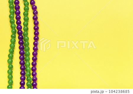 purple and green beads on yellow background Top view 2022 Mardi Gras Parade Schedule Mockup Copy space. purple and green beads on yellow background Top view 2022 Mardi Gras Parade Schedule Mockup Copy space. 104238685