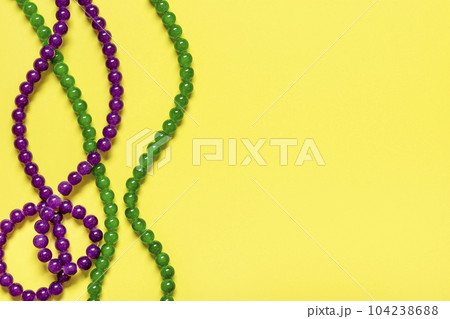 purple and green beads on yellow background Top view 2022 Mardi Gras Parade Schedule Mockup Copy space. purple and green beads on yellow background Top view 2022 Mardi Gras Parade Schedule Mockup Copy space. 104238688
