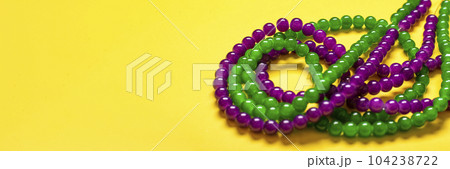 purple and green beads on yellow background Top view 2022 Mardi Gras Parade Schedule Mockup Copy space. purple and green beads on yellow background Top view 2022 Mardi Gras Parade Schedule Mockup Copy space. 104238722