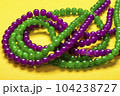 purple and green beads on yellow background Top view 2022 Mardi Gras Parade Schedule Mockup Copy space. 104238727