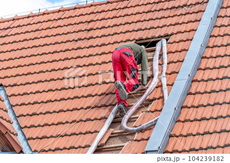 craftsman on the stairs, blowing foam roof insulation, application with the help of a pressure hose 104239182