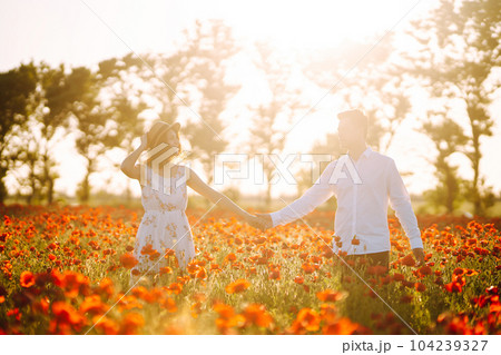 Loving couple in the poppy field at sunset. Enjoying time together. love and lifestyle. 104239327