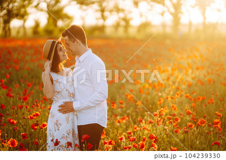 Loving couple in the poppy field at sunset. Enjoying time together. love and lifestyle. 104239330