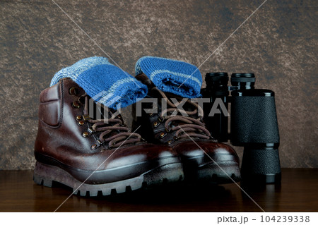 Hiking Boots and Socks with Binoculars on a Varnished Table Top 104239338