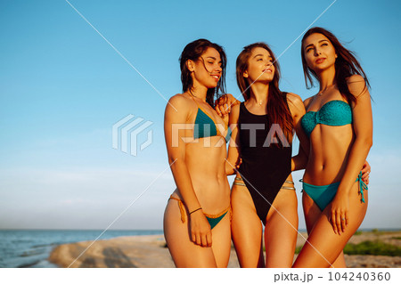 Portrait of three beautiful girls on the beach. Young women enjoying on beach holiday. Summer holidays. 104240360