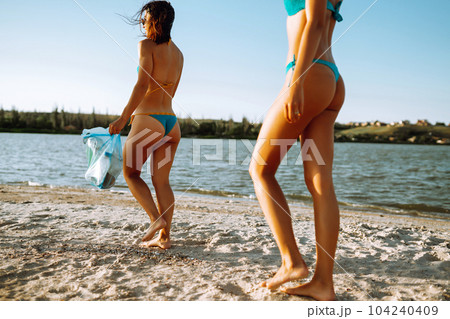 Three young girls pick up trash on the beach. Environmental pollution.  Ecological problem. Stock Photo by maxbelchenko
