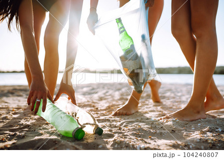 Three young girls pick up trash on the beach. Environmental pollution. Ecological problem. Three young girls pick up trash on the beach. Environmental pollution. Ecological problem. 104240807