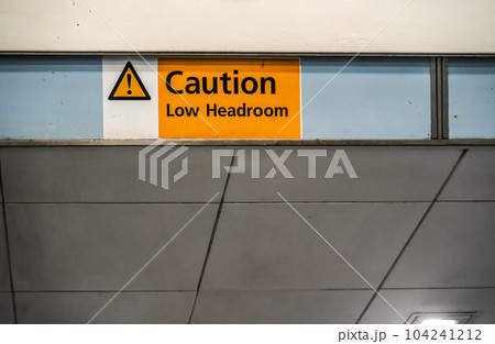 Orange " Caution low headroom " sign on roof above elevators 104241212