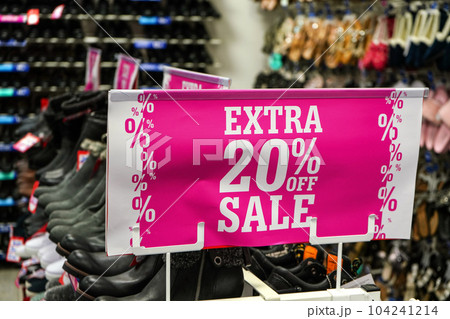 Bright pink Extra 20 percent off sale sign at shoe shop. 104241214