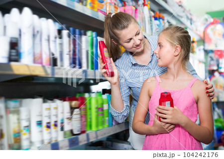 Positive woman with girl choosing shampoo Positive woman with girl choosing shampoo 104242176
