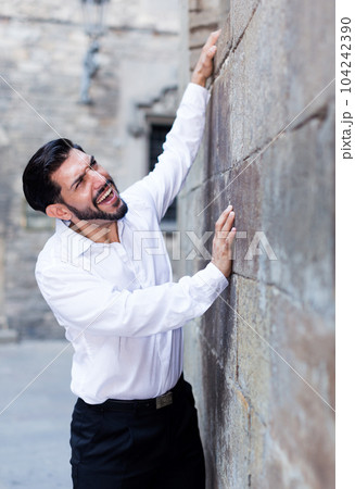 Man trying to climb stone wall Man trying to climb stone wall 104242390