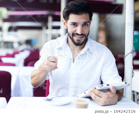 Man drinking coffee in summer cafeteria 104242516