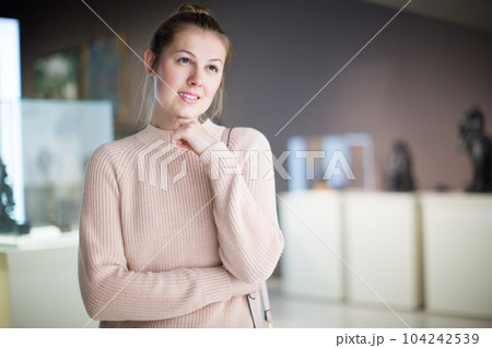 Young female visitor looking at art exhibition 104242539