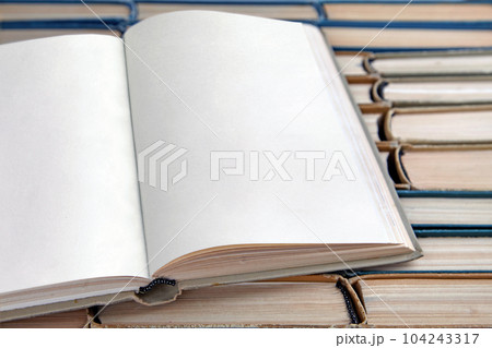 Open vintage book or notebook with blank pages lies on the background of a row of shabby books Open vintage book or notebook with blank pages lies on the background of a row of shabby books 104243317